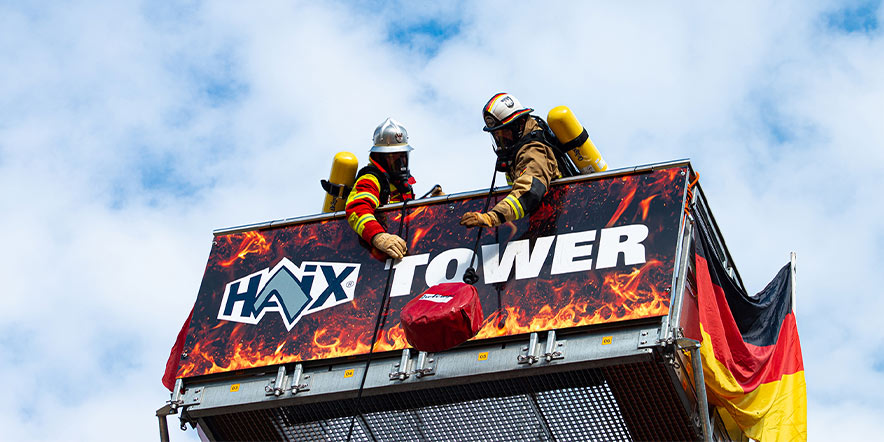 Zwei Feuerwehrmänner ziehen die Schlauchpakete am Wettkampfturm nach oben