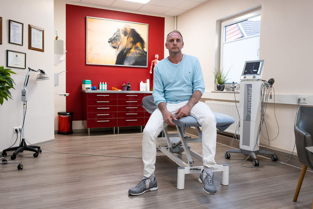 Magnus Hirschfeld sitzt auf einer Liege in seiner Praxis